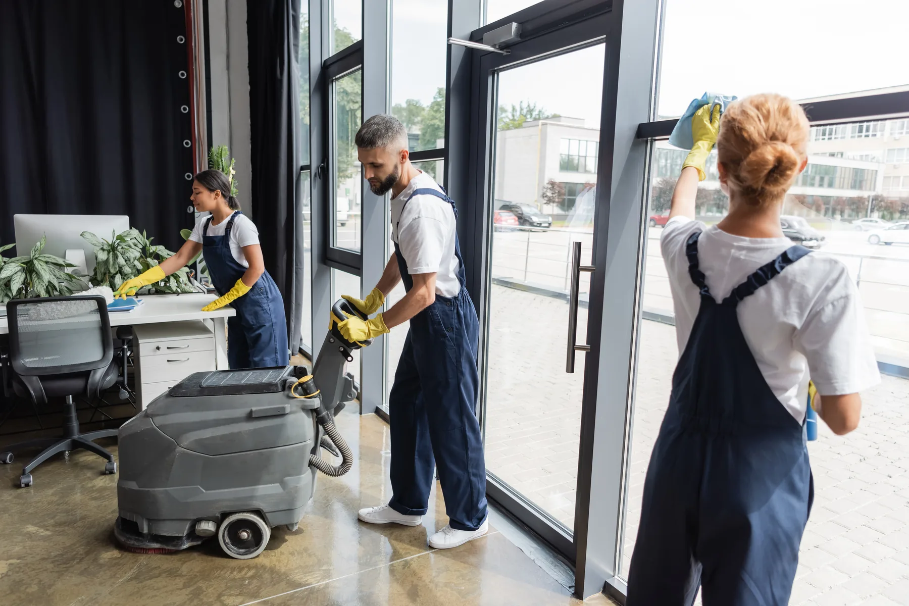 Un equipo de limpieza trabajando en una oficina, una persona operando una fregadora de piso