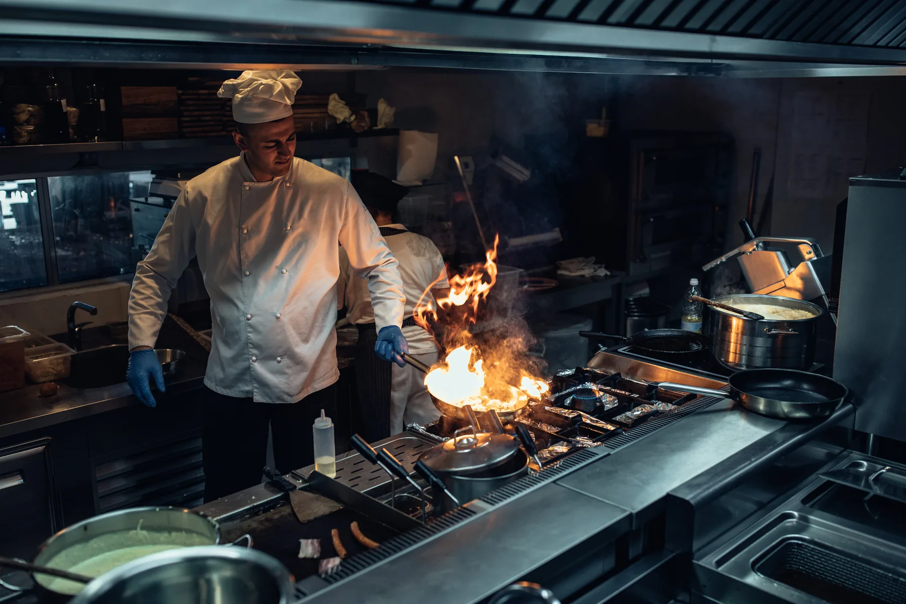 Un chef trabajando en una estufa comercial encendida, en una cocina profesional
